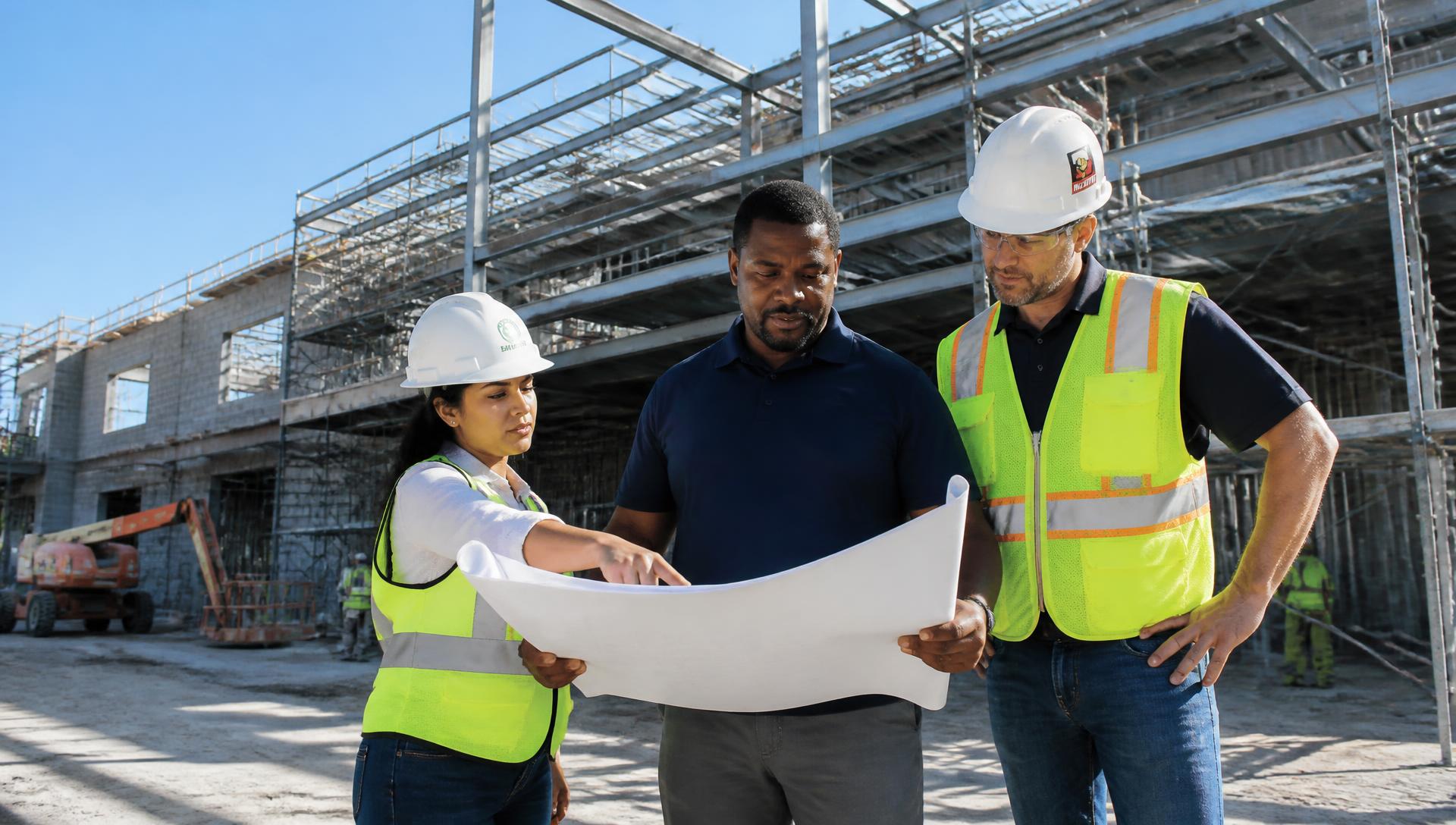 General contractor and diverse subcontractor leaders reviewing plans on an active commercial jobsite